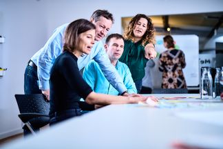 e-pixler-Mitarbeiter diskutieren gemeinsam an einem Tisch über ein Projekt.