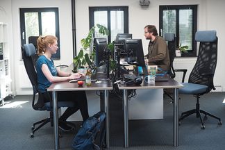 Zwei Mitarbeiter bei e-pixler arbeiten an ihren Schreibtischen in einem modernen Büro.