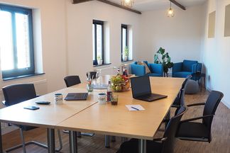 Kleiner Konferenzraum bei e-pixler mit einem Tisch, Stühlen und Sofas.