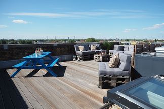 Dachterrasse bei e-pixler mit Sitzgelegenheiten und einem blauen Tisch.